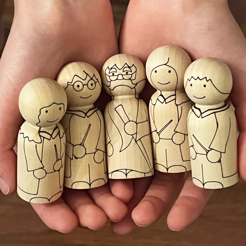 Child's hands holding five wizard and witch wooden peg doll characters